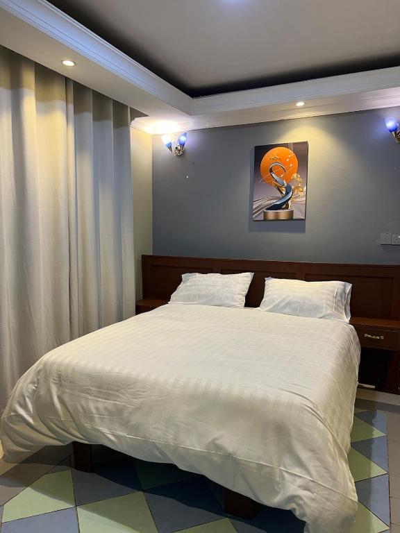 a bedroom with a large bed with white sheets at Capri Hills 4 in Mwanza