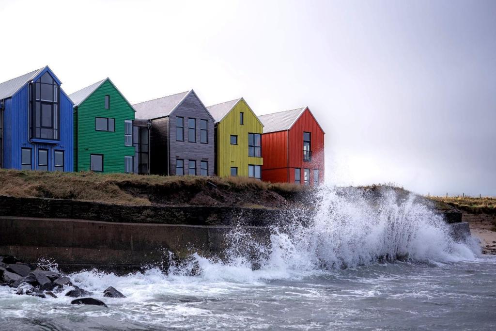 a group of colorful houses next to a body of water at Pennan - 2 Bed Luxury Apartment by Together Travel in Wick