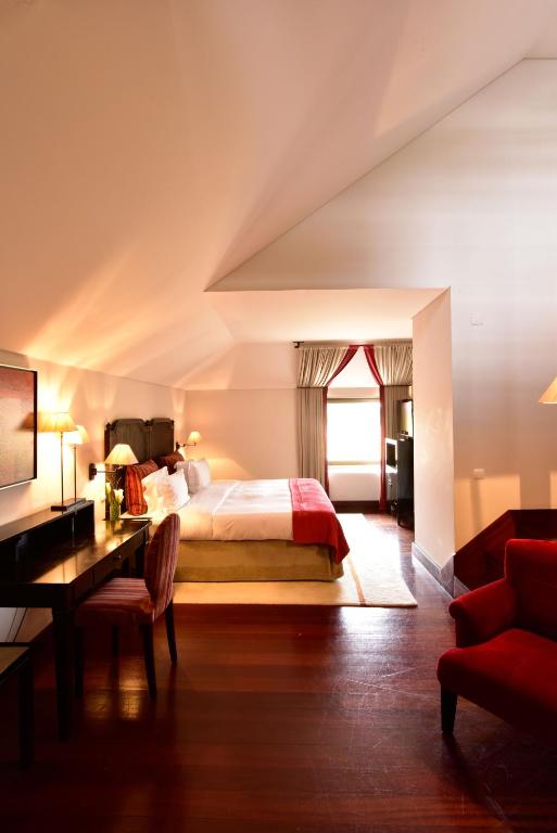 een slaapkamer met een bed, een bureau en een raam bij Pousada Convento de Tavira in Tavira
