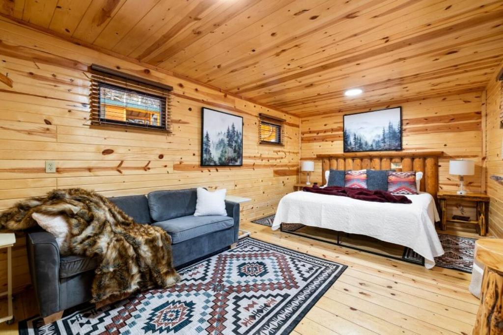 a bedroom with a couch and a bed in a log cabin at Bison Trail House- Rustic Cabin Retreat in Rapid City