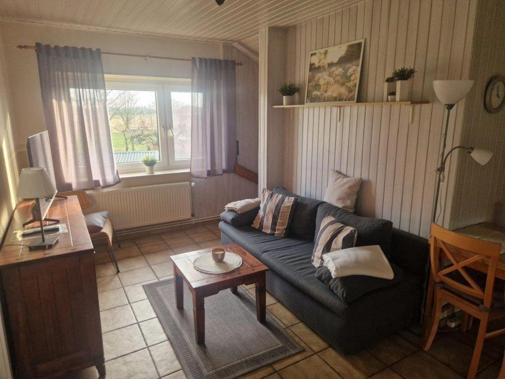 a living room with a blue couch and a table at Feldblick in Ruhwinkel