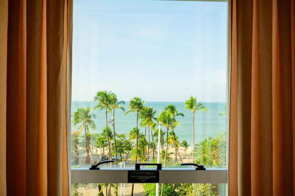 a window with a view of the ocean and palm trees at Hotel Beira Mar in Fortaleza