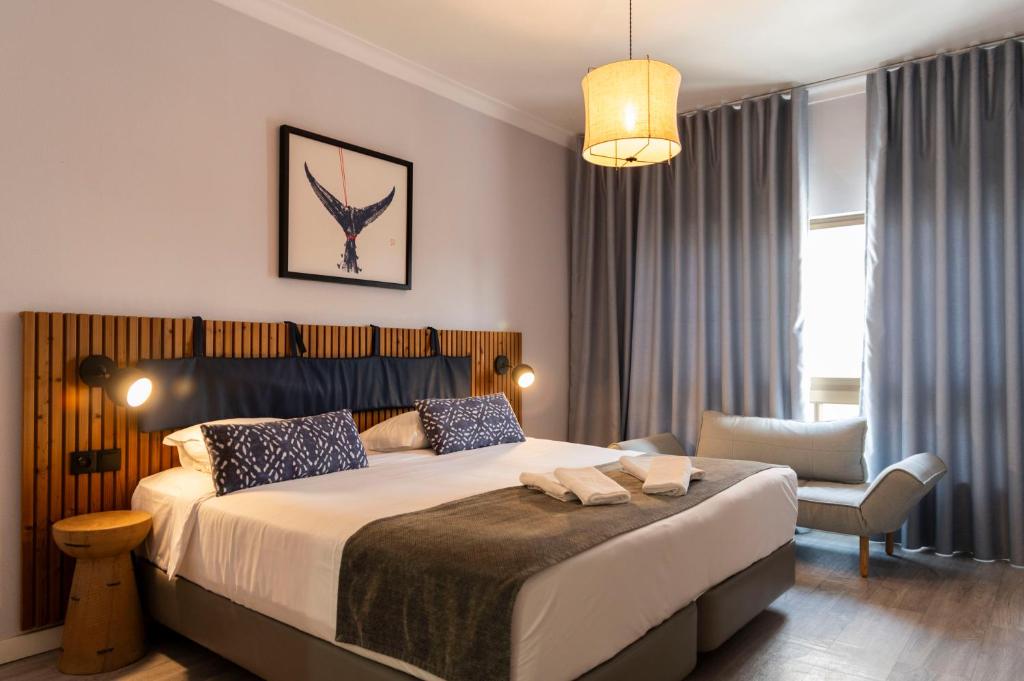 a bedroom with a bed and a chair in a room at WOT Costa da Caparica Soul in Costa da Caparica