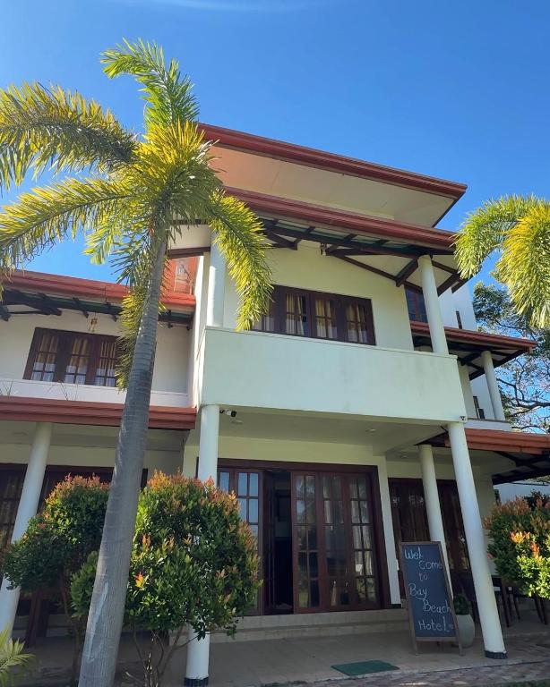 a building with a palm tree in front of it at Bay Beach Hotel Nilaveli in Kumpurupiddi