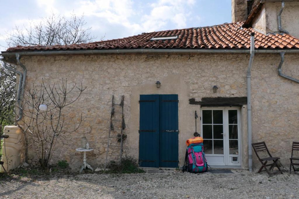 a person standing in front of a house with a blue door at Le Moulin du Clapier - La Ficelle in Sorges