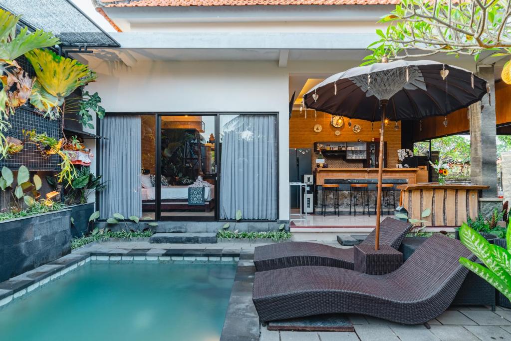 a swimming pool with two chairs and an umbrella at Meliora bali villa in Ubud