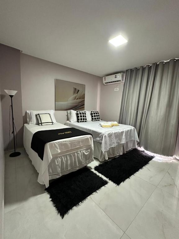 a bedroom with two beds and a rug at Flat JK 201 in Juazeiro do Norte