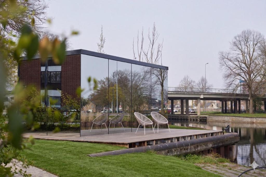 two chairs sitting on a dock next to a building at HANNAH Mirror Tiny House in Den Bosch