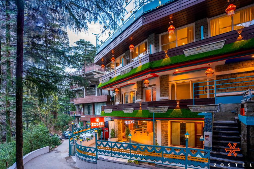 a building with a sign on the side of a street at Zostel McLeodganj in McLeod Ganj