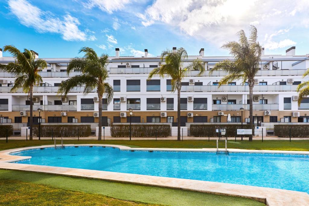 a hotel with a swimming pool in front of a building at Las Dunas 213 - by Welcomely in Oliva