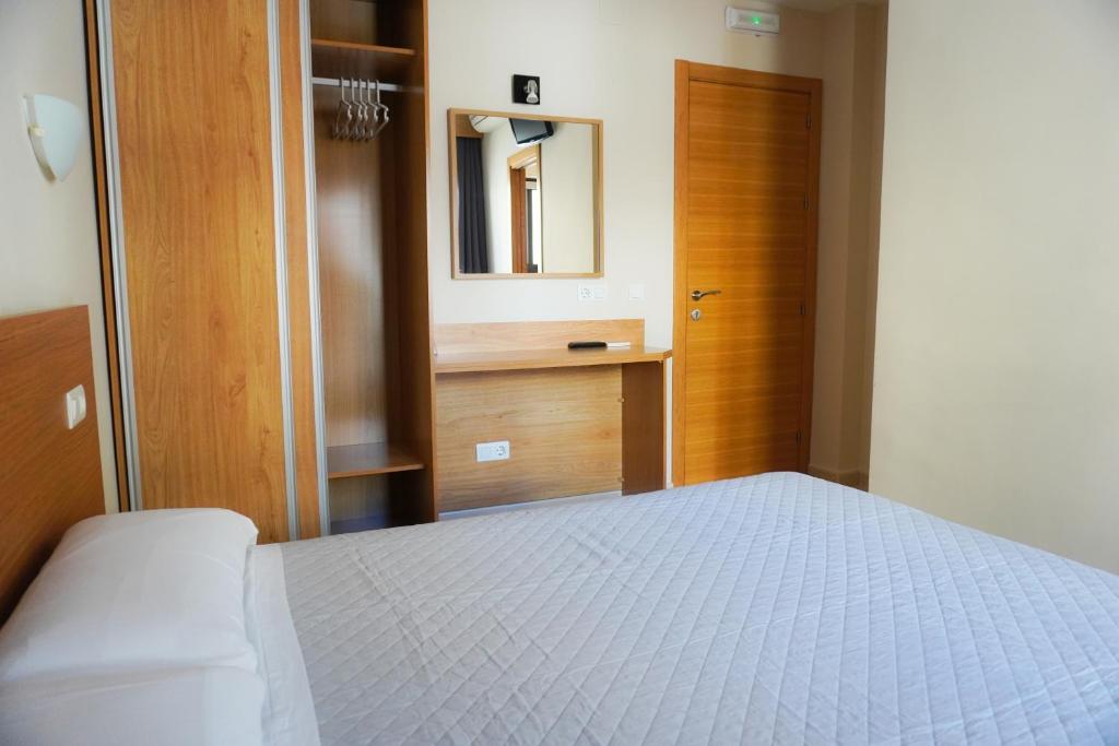 a bedroom with a bed and a mirror and a door at Hostal Costabella in Fuengirola