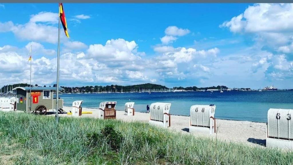 a beach with a row of white chairs and the water at Ostsee No8 Eckernförde in Eckernförde
