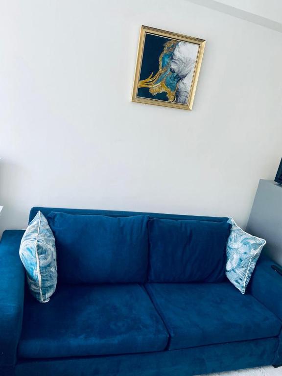 a blue couch in a living room with a picture on the wall at Haven stay in Kiambu