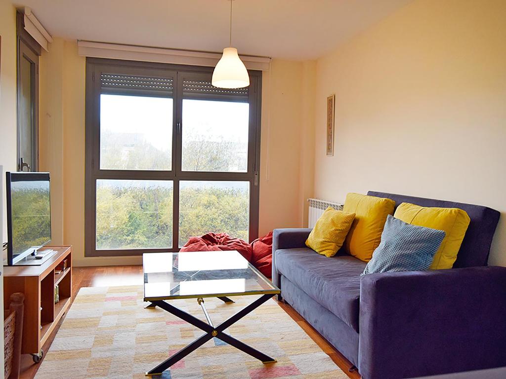 a living room with a purple couch and a glass table at Apartamentos Las Margas Sabiñánigo 3000 in Sabiñánigo