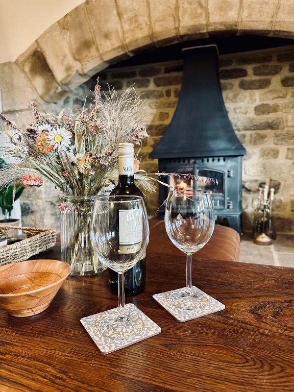 two wine glasses sitting on a table with a bottle of wine at Moorlands Farm Holidays in Keighley