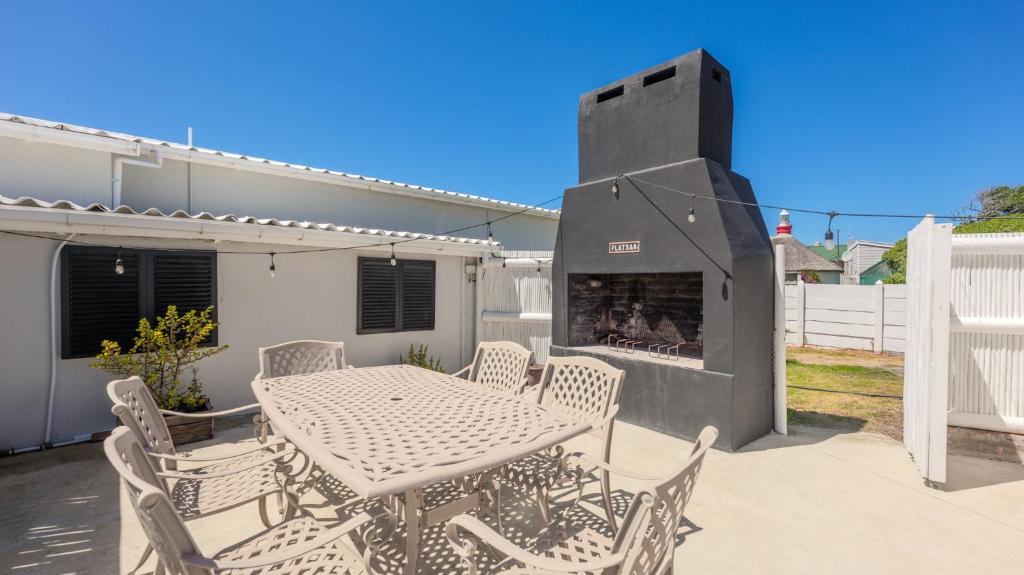 a patio with a table and chairs and a fireplace at 206 On Main in Agulhas