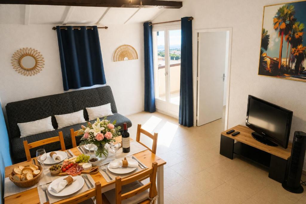 a living room with a table and a television at Le Sun Piscine Tennis parking Vue mer wi-fi climatisation in Fleury