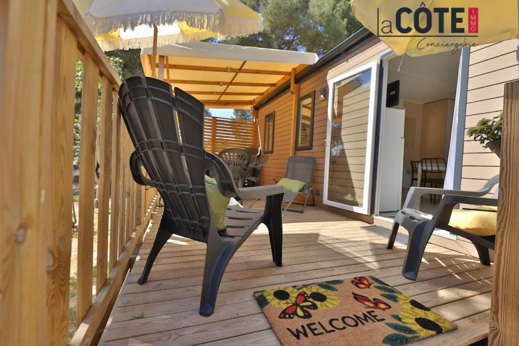 a deck with two chairs and a welcome mat at Lou Soleil - Bungalow - 6 couchages in Carry-le-Rouet