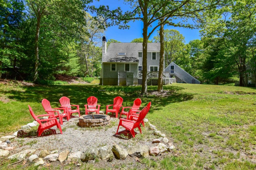 a group of red chairs sitting around a fire pit at Spacious Stone Fire Pit Game Room in Barnstable