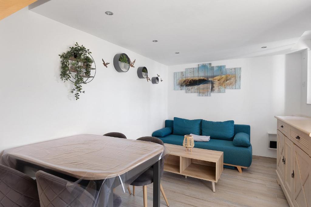a living room with a blue couch and a table at Petit gîte bleu jusqu'à 4 personnes in Huillé