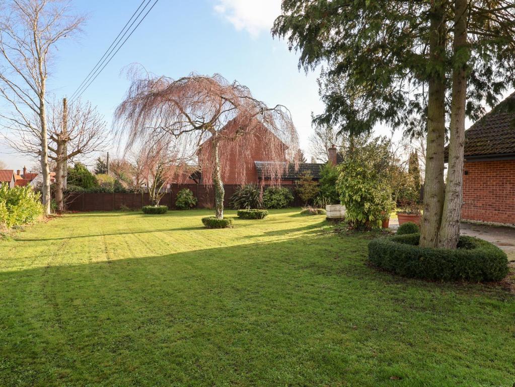 a yard with a tree and a brick building at Three Ways in Diss