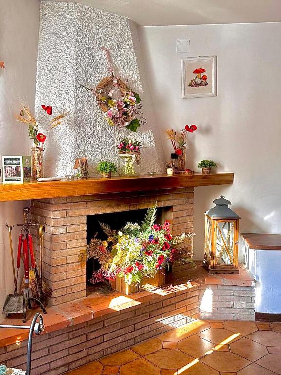 a living room with a brick fireplace with flowers on it at Il Bosco Guest House Subiaco in Subiaco
