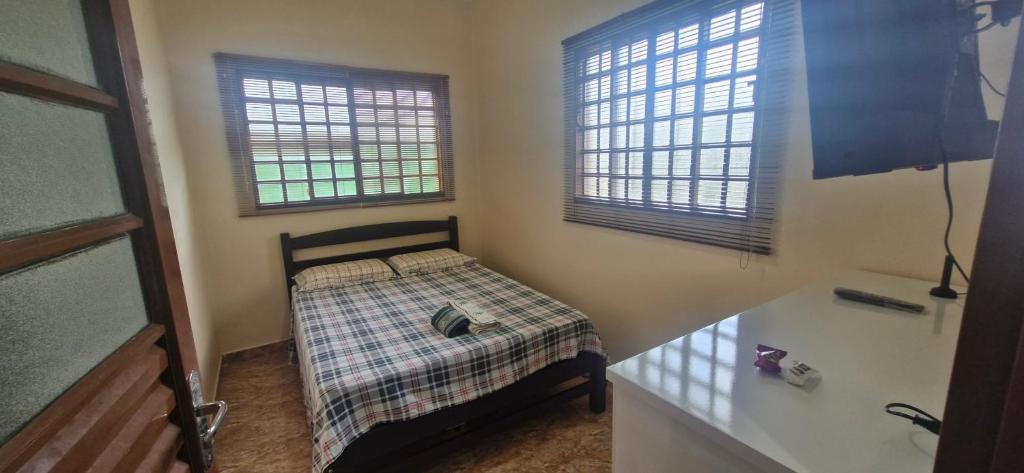 a small bedroom with a bed and two windows at Canto dos Pássaros in Brasília