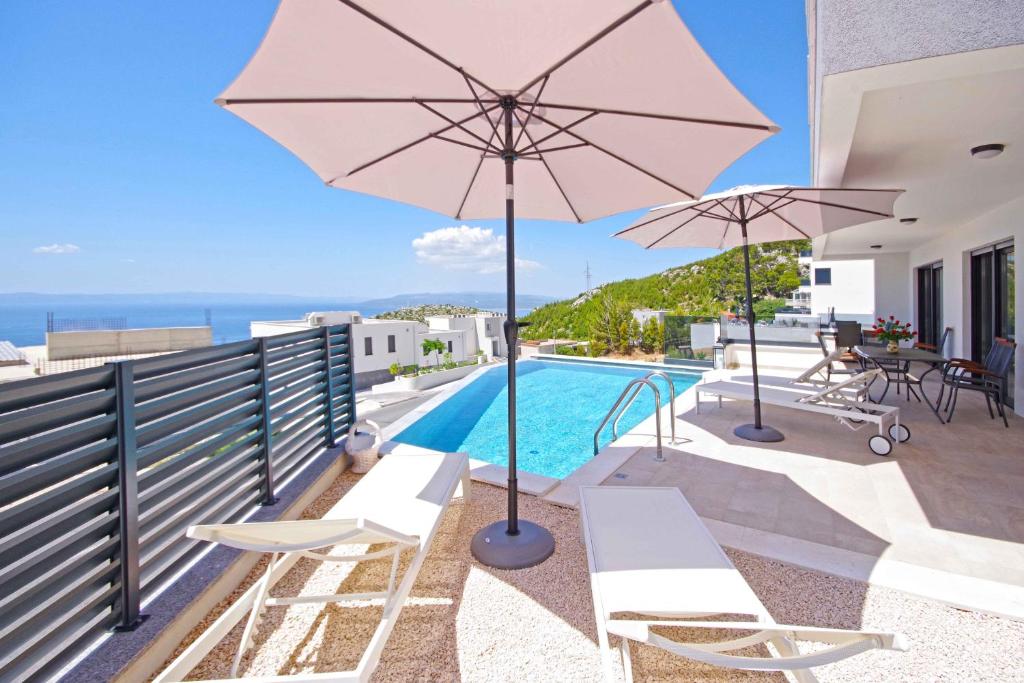 a villa with a swimming pool and an umbrella at Sunset Apartments in Makarska