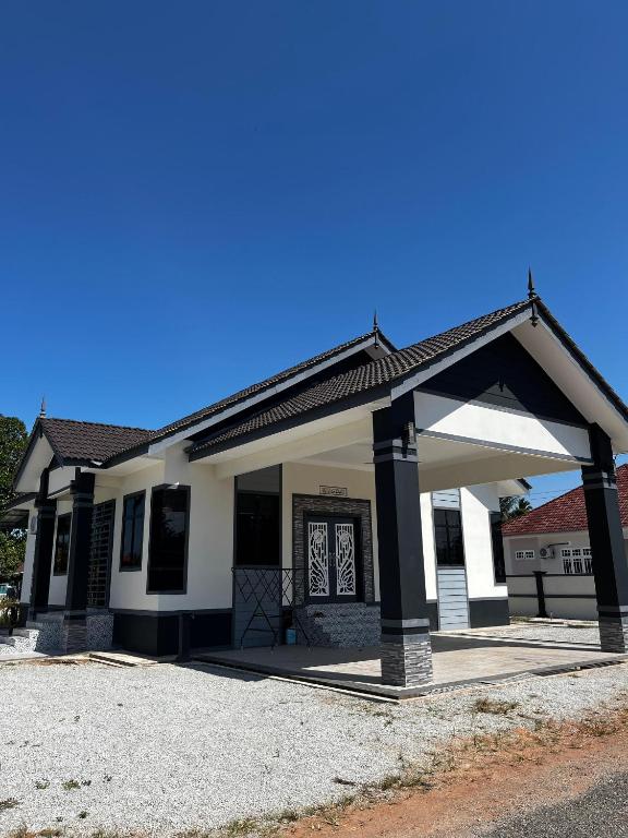 a small white house with a large garage at HomeStay Rafiza in Jertih