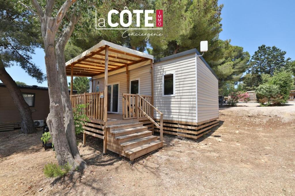 a tiny house with a porch and stairs next to a tree at Bleu Paradou - Bungalow - 6 couchages in Carry-le-Rouet