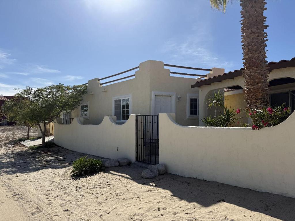 a white house with a fence and a palm tree at Casa Stu Playa de Oro Rental in San Felipe