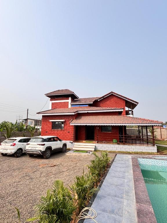 a red brick house with cars parked in front of it at BlueSea Villa Kashid beach in Kashid