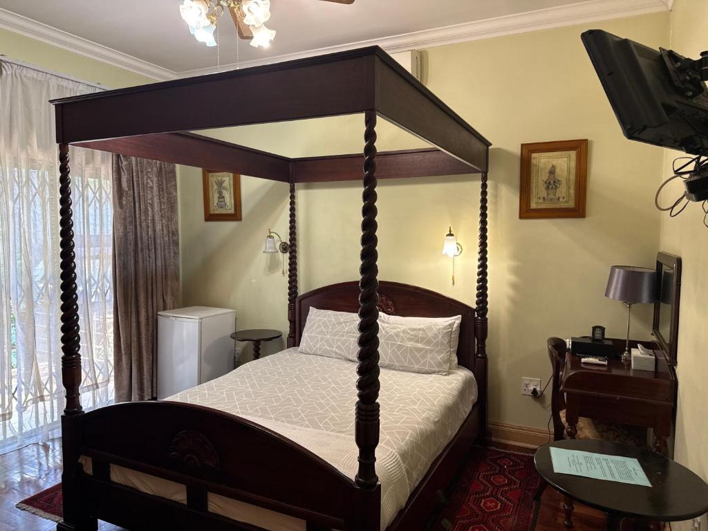 a bedroom with a canopy bed with a white bedspread at 45 on Mendelssohn in Johannesburg