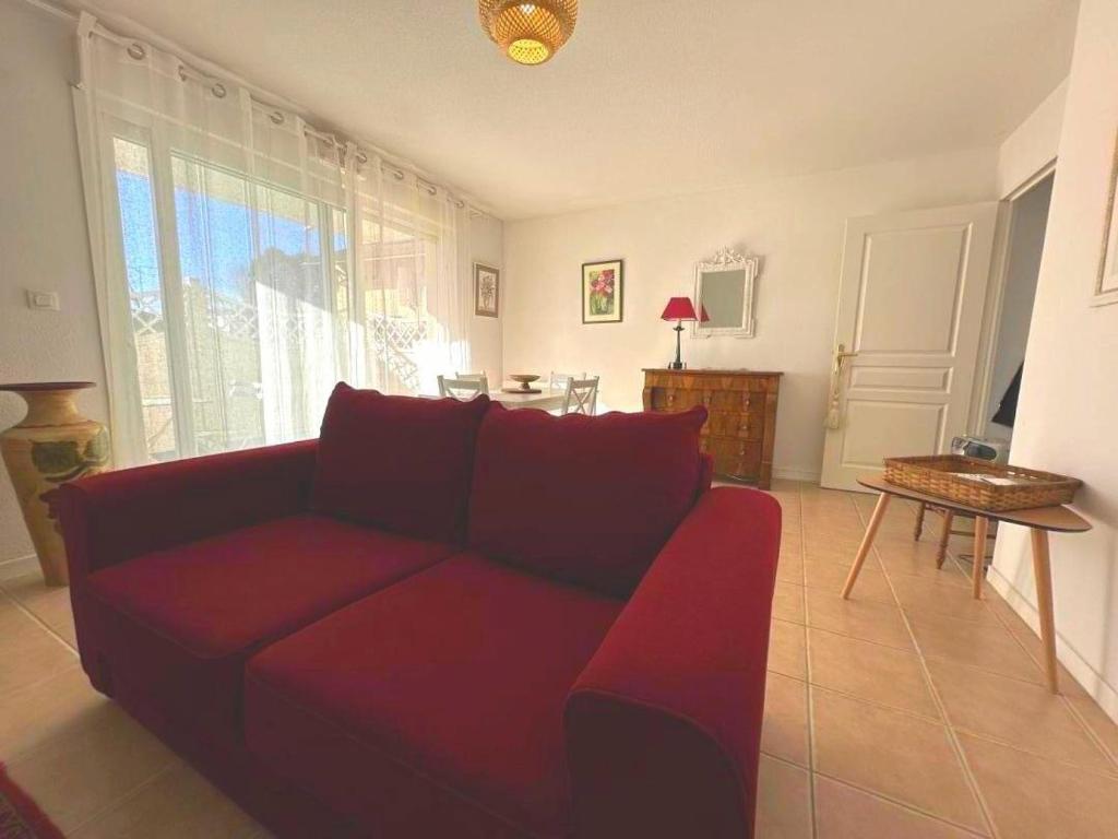 a living room with a red couch and a table at L'appartement la rochebardière in Saint-Paul-lès-Dax