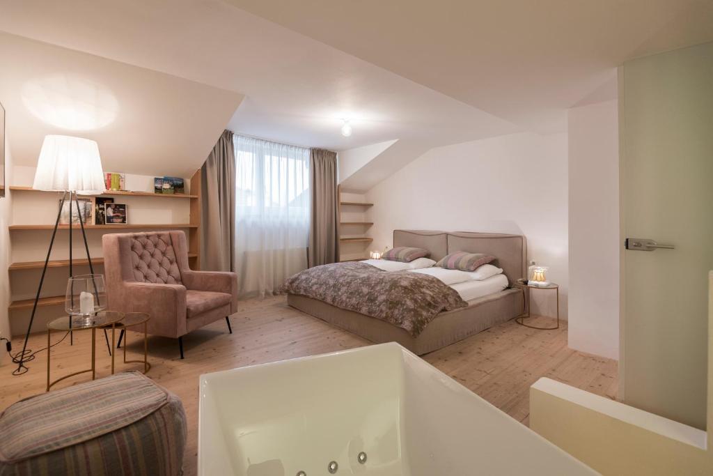 a hotel room with a bed and a chair at Gius La Diffusa in Caldaro