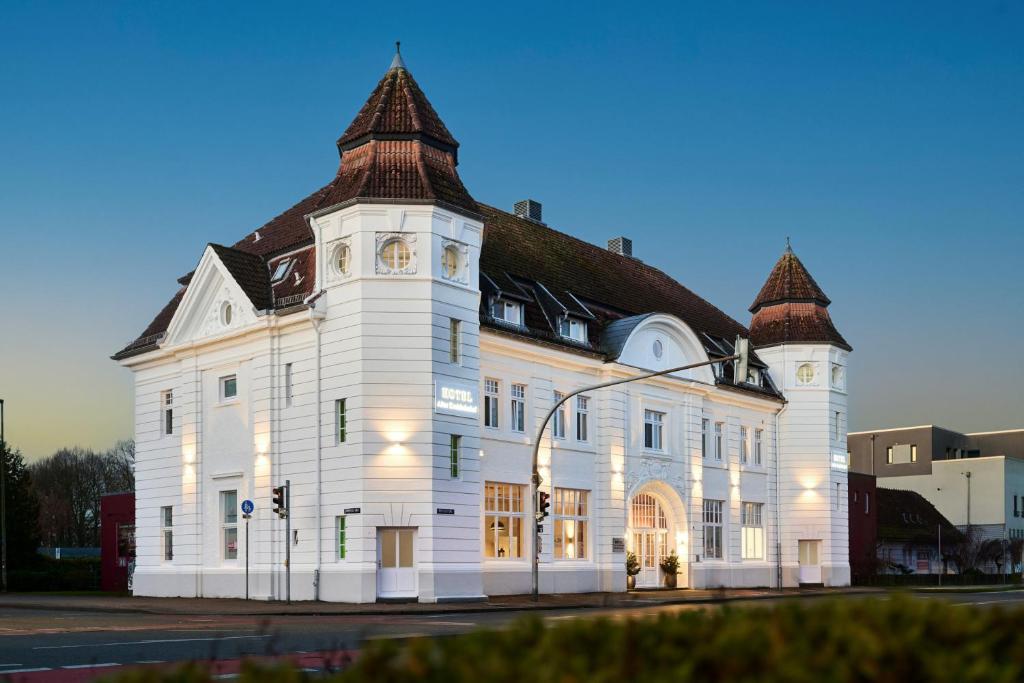 a large white building with a clock tower at Hotel Alter Kreisbahnhof in Schleswig