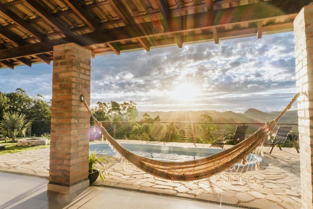 a hammock on a patio with a view of a pool at Chalé 1 Refúgio do Sol Piscina com Vista para Montanas in Socorro