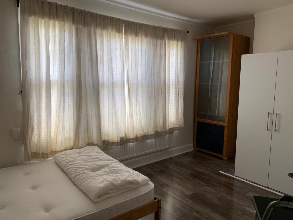 a bedroom with a bed and a large window at M Studio in Raynes Park