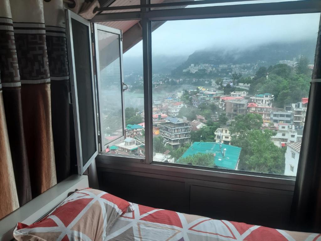 a bedroom window with a view of a city at Rahul Residency Homestay- Couple & Family friendly- 'prime location- Easy access to Mall Rd- WiFi- Smart TV - Kitchen- City view in Solan