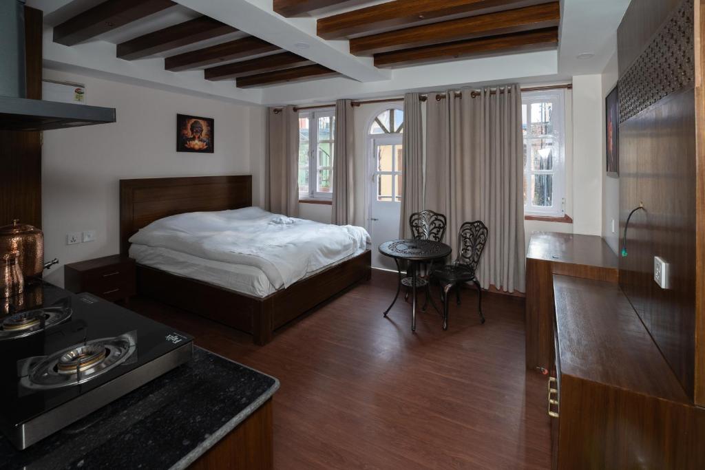 a bedroom with a bed and a table and a kitchen at Fizzy Stay in Jawlakhel