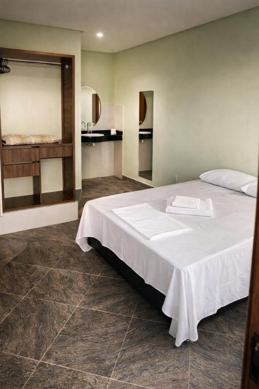 a bedroom with a large white bed and a kitchen at Rio Preto Hotel in Formosa