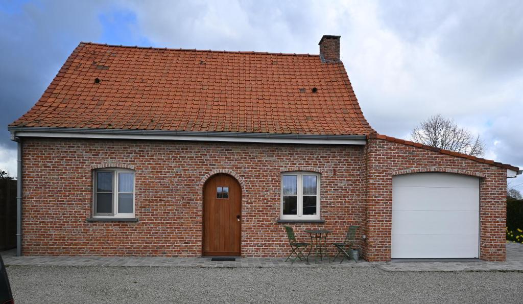 a red brick house with a white garage at Huis van de Koekuit in Moorslede