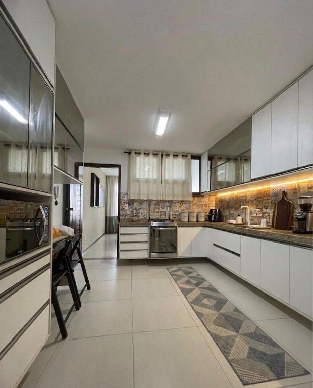 a large kitchen with white cabinets and a table at Star HOUSE beach in Aracaju