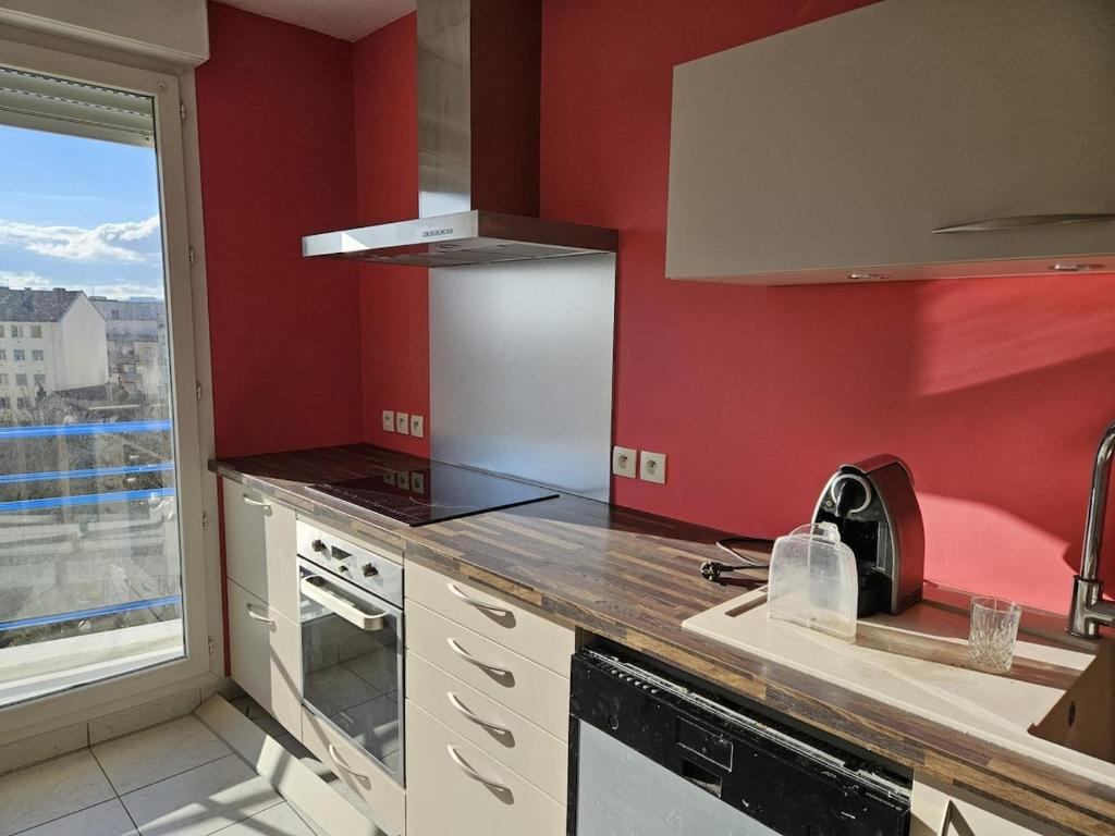a kitchen with red walls and a large window at La maison de Pommard in Dijon
