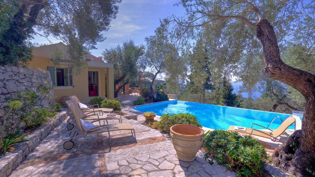 a swimming pool with benches and a house at Villa Petra in Arvanitakaíïka