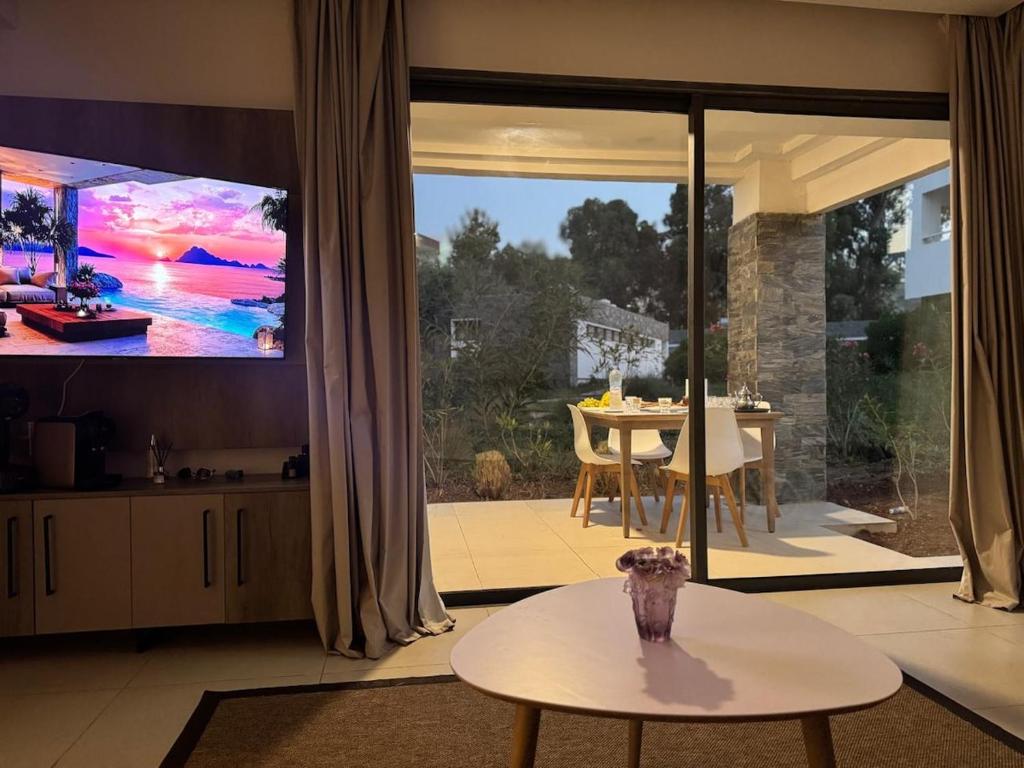 a living room with a large tv and a table at Apparemment à Radisson Blu Apartment Alhoceima Beach Access in Al Hoceïma