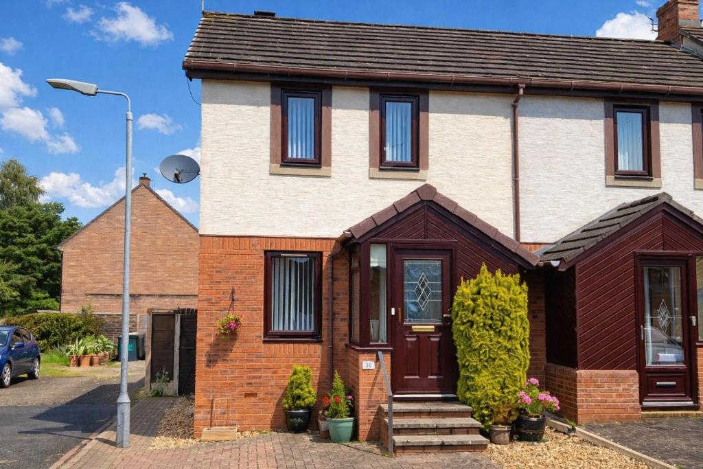 a brick house with a brown door at Beckside Garden Brampton, ideal family cottage close to Hadrians Wall in Brampton