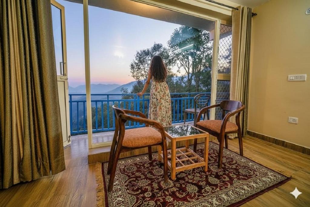 a woman standing on a balcony looking out at the view at Mountain Golden Ray in Mukteshwar