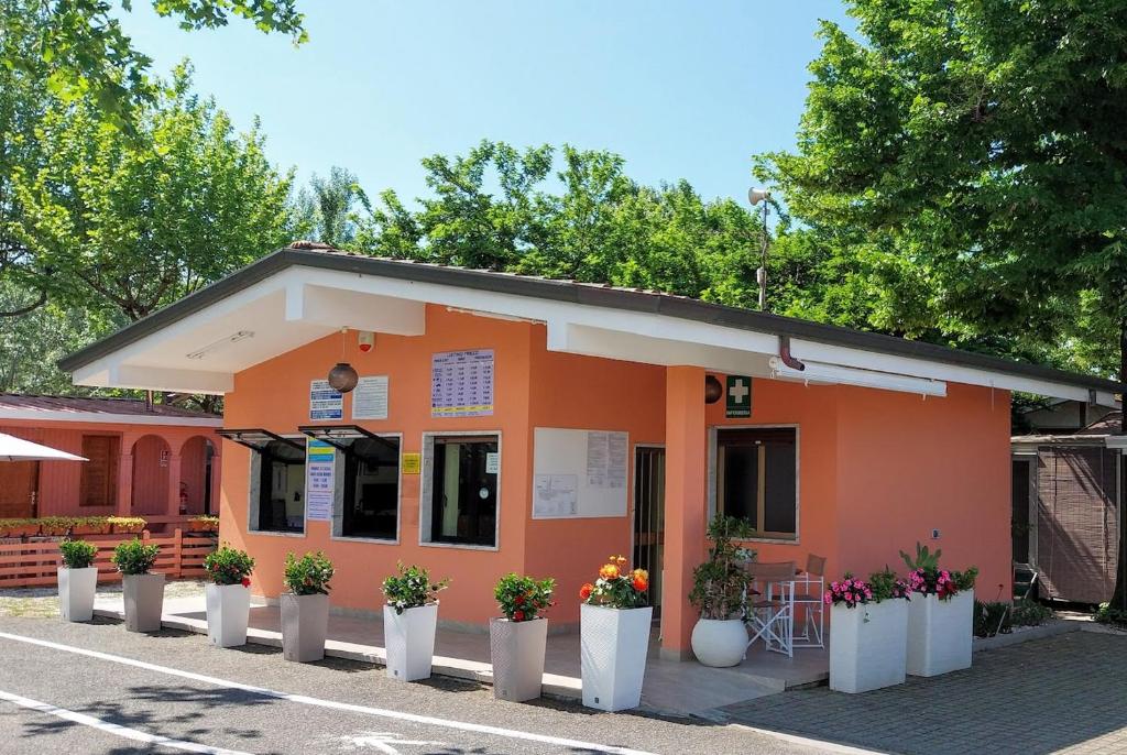 an orange building with potted plants in front of it at CAMPING CALATELLA parco di vacanza in Marina di Massa