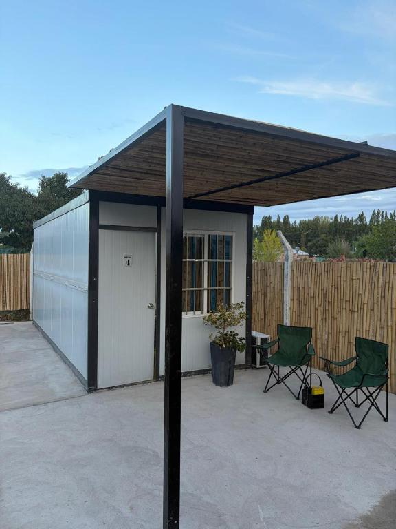a pavilion with two chairs and a white garage at Amanecer Rio Limay 2 in Plottier